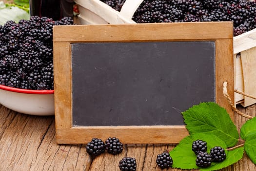 Slate board with text area in front of freshly harvested blackberries