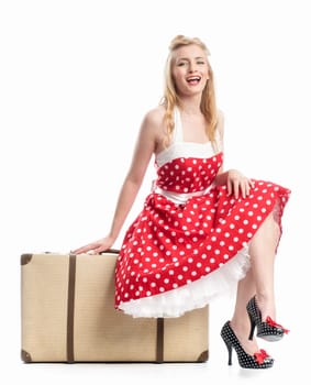 a woman in a summer dress sits on a suitcase and waits