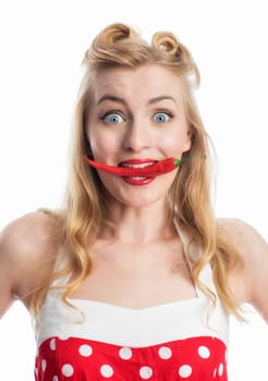 a woman in rockabilly style bites on a chilischote and rips the eyes wide open