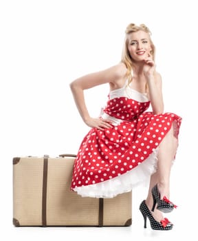 a pinup girl sitting waiting on a suitcase