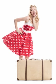 an astonished woman in a summer dress stands behind a suitcase