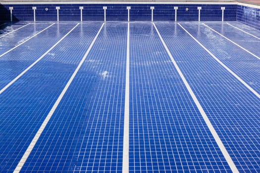 Swimming pool with blue ties and swim lane tile markings empty of water for maintenance