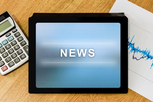 news word on digital tablet with calculator and financial graph