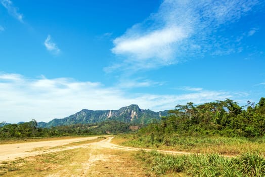 View of a dirt road and green jungle covered hills in Rurrenabaque, Bolivia