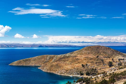 Terraced landscape of Isla del Sol with Andes mountains in the background on the Bolivian side of Lake Titicaca