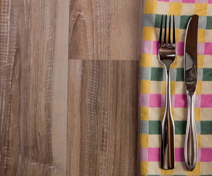 Tableware towel plaid with fork and knife on rustic wooden background