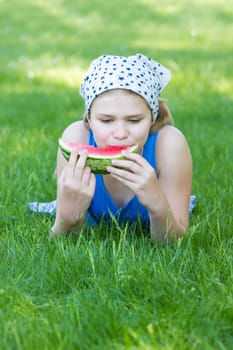 cute little girl eating watermelon on the grass