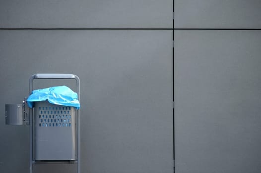 The photograph of a garbage can on a modern house wall.