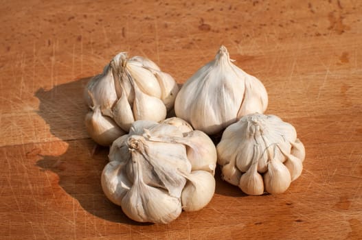 Four garlic cloves on wooden board background