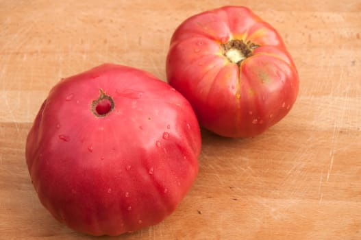 Two organic tomatoes on wooden board backgound