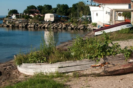 Crumbling old wooden fishing boat full of plants at sea beach near fishing village