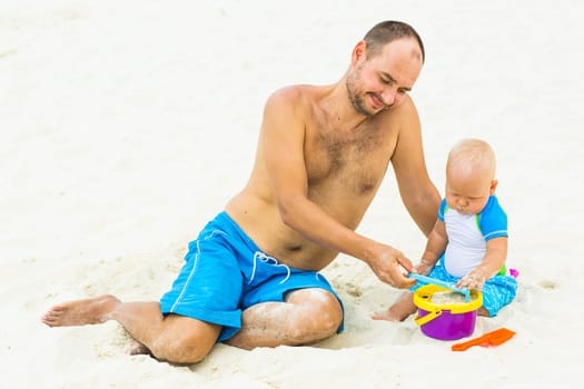 Baby and father on the tropical beach playing toys