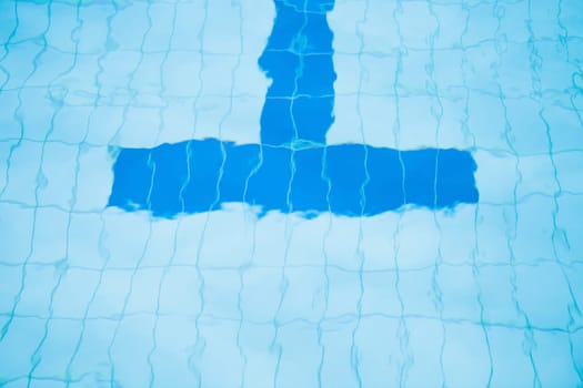 Closeup of bottom lane line at end of swimming pool with T-shape slightly distorted by water