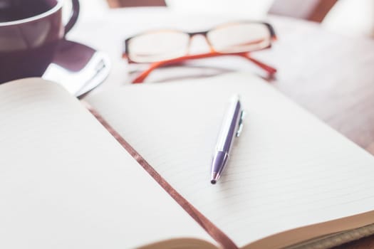 Pen on notebook with coffee cup and eyeglasses, stock photo