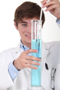 Young chemistry student stirring blue liquid in a glass graduated cylinder