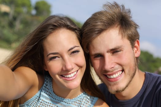 Couple photographing a selfie with the smart phone or digital camera outdoors in the mountain