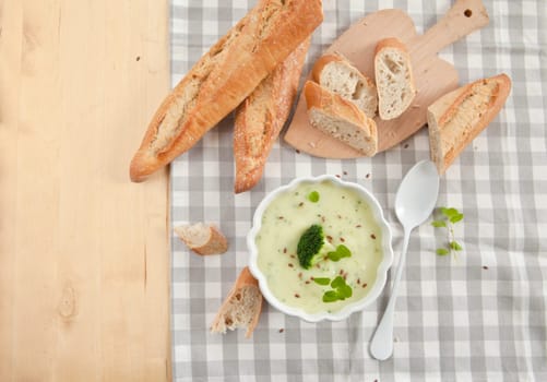 Homemade cream soup with broccoli and fresh baguette