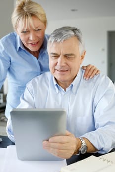 Senior couple looking at bank account on digital tablet