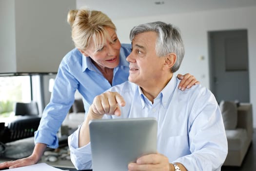 Senior couple looking at bank account on digital tablet