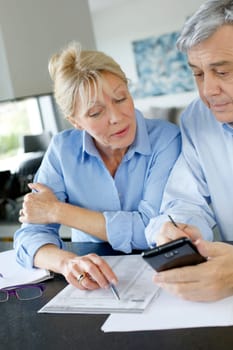 Senior couple calculting bills amount using smartphone