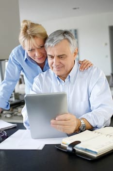 Senior couple looking at bank account on digital tablet