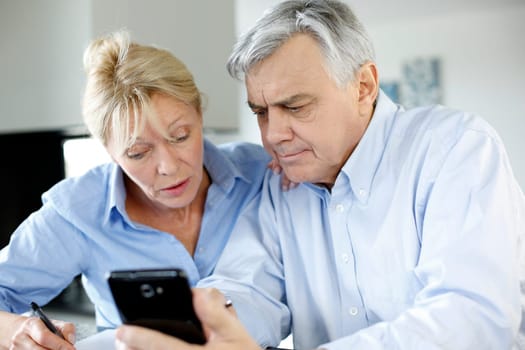 Senior couple calculting bills amount using smartphone