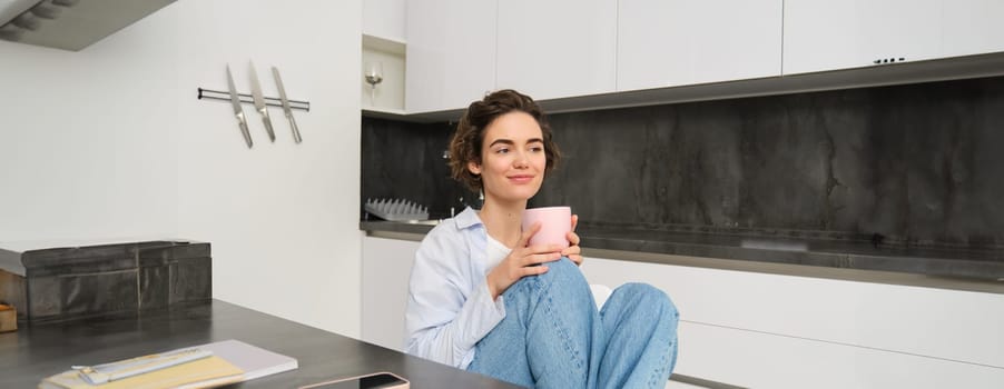 Image of young adult woman with cup of coffee. Girl relaxed at home, drinks tea, has a break from work. People and lifestyle concept