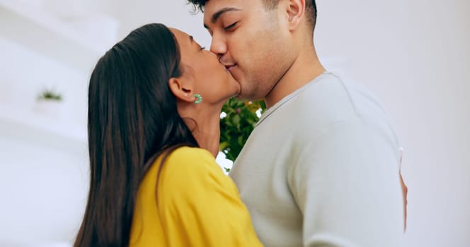 Love, hug and a couple kissing closeup in their home for romance while bonding together on their anniversary. Face, happy or relationship with a man and woman embracing for care on valentines day.