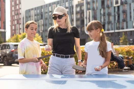 Family playing table tennis in the summer outdoors. High quality photo