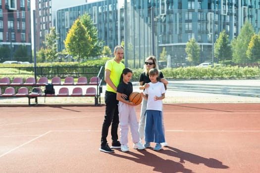 summer holidays, sport and people concept - happy family with ball playing on basketball playground. High quality photo