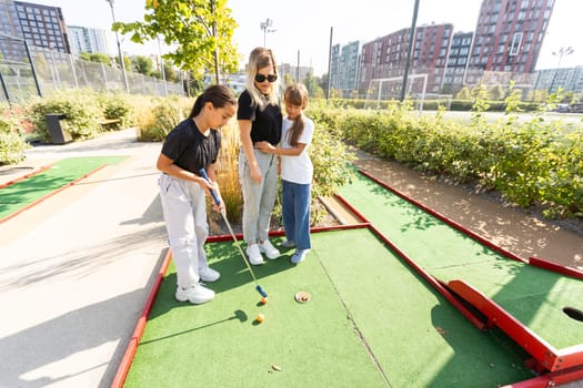 Group of two funny kids playing mini golf, children enjoying summer vacation. High quality photo