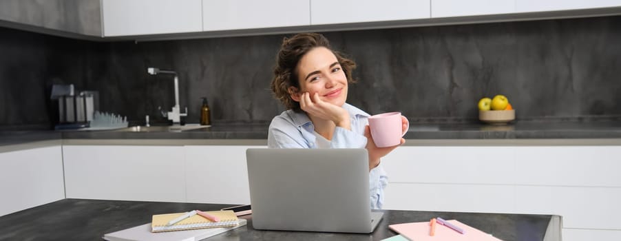 Portrait of 25 years woman, studies online, watches course in internet, works on laptop from her home.