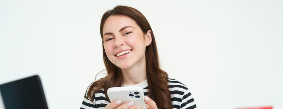 Portrait of girl with smartphone laughing, using mobile phone app, isolated on white background.