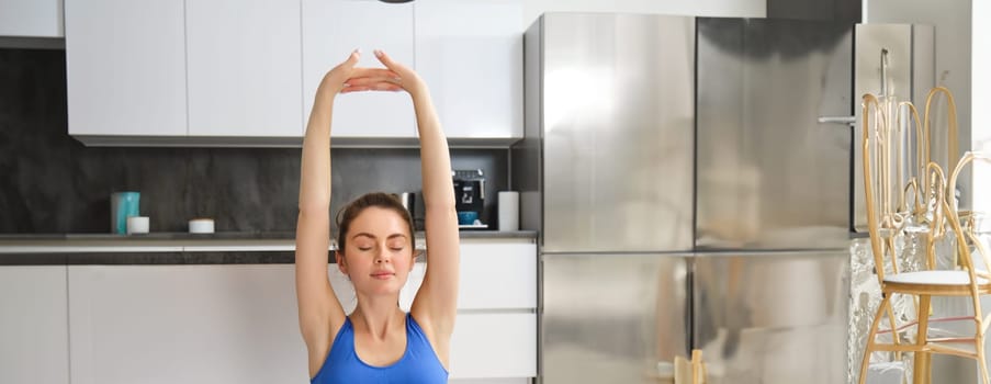 Portrait of beautiful young woman, doing training at home, fitness workout on rubber yoga mat in living room.