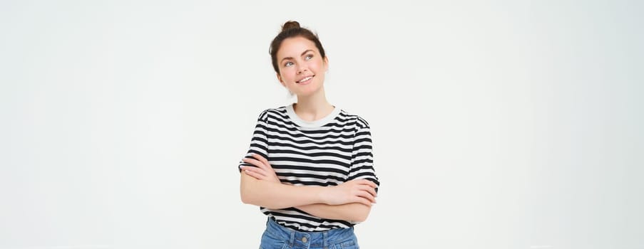 Image of happy, beautiful young woman dreaming, thinking of something with pleased smile, looking at upper left corner thoughtful, white background.