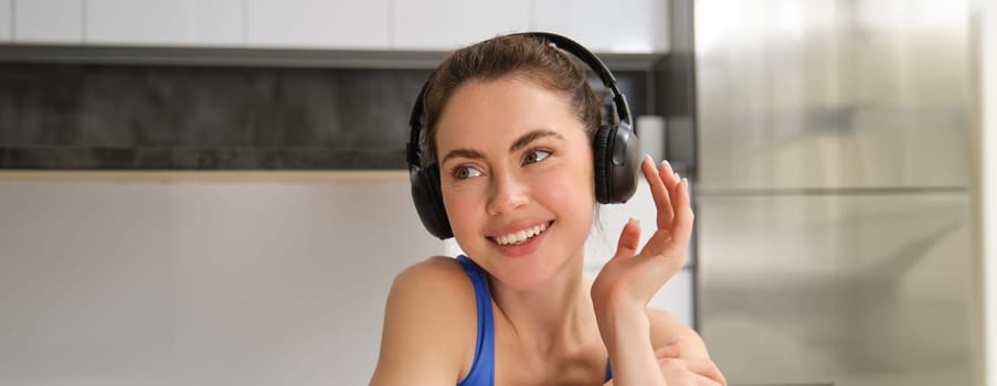 Close up portrait of attractive young smiling woman, workout, doing fitness training, listening music in headphones. Fitness and wellbeing concept