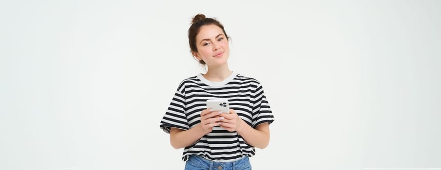 Image of young smiling woman, holding mobile phone, using smartphone application, isolated over white background.