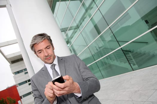 Businessman writing short message on mobile phone