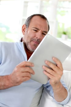 Senior man at home using electronic tablet