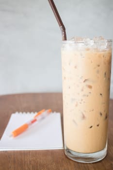 Glass of cold milk coffee on wooden table, stock photo