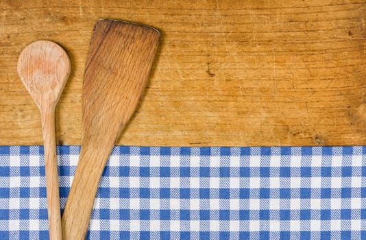 Wooden background with checkered tablecloth and cooking spoon