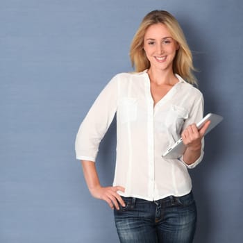 Young woman standing on grey background with touchpad