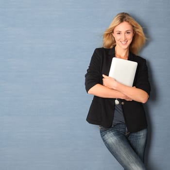 Beautiful woman leaning on wall with touchpad