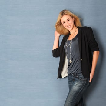 Beautiful charming woman leaning on blue wall