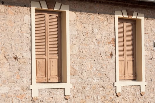 Two closed wooden windows on stone house wall