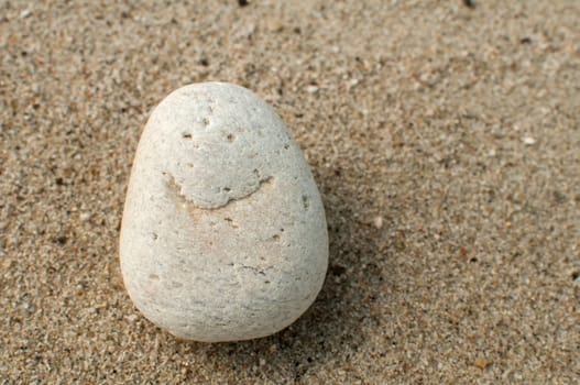 Naturally received image of smile on sea pebble stone on sand background