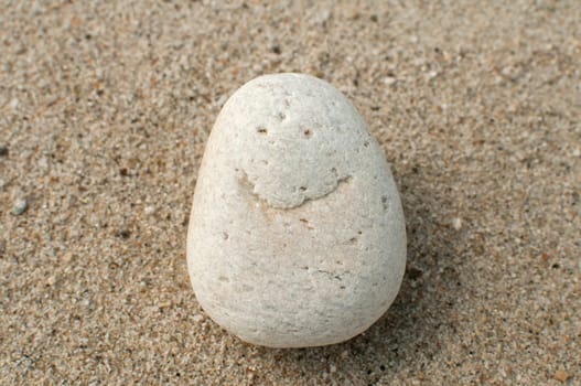 Naturally received image of smile on sea pebble stone on sand background
