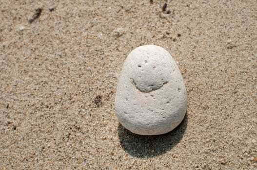 Naturally received image of smile on sea pebble stone on sand background