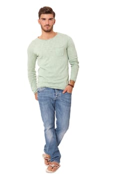 good-looking young man with beard posing with his hands in his pockets in jeans and sandals isolated on white background