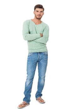 good-looking young man with beard posing with his hands in his pockets in jeans and sandals isolated on white background